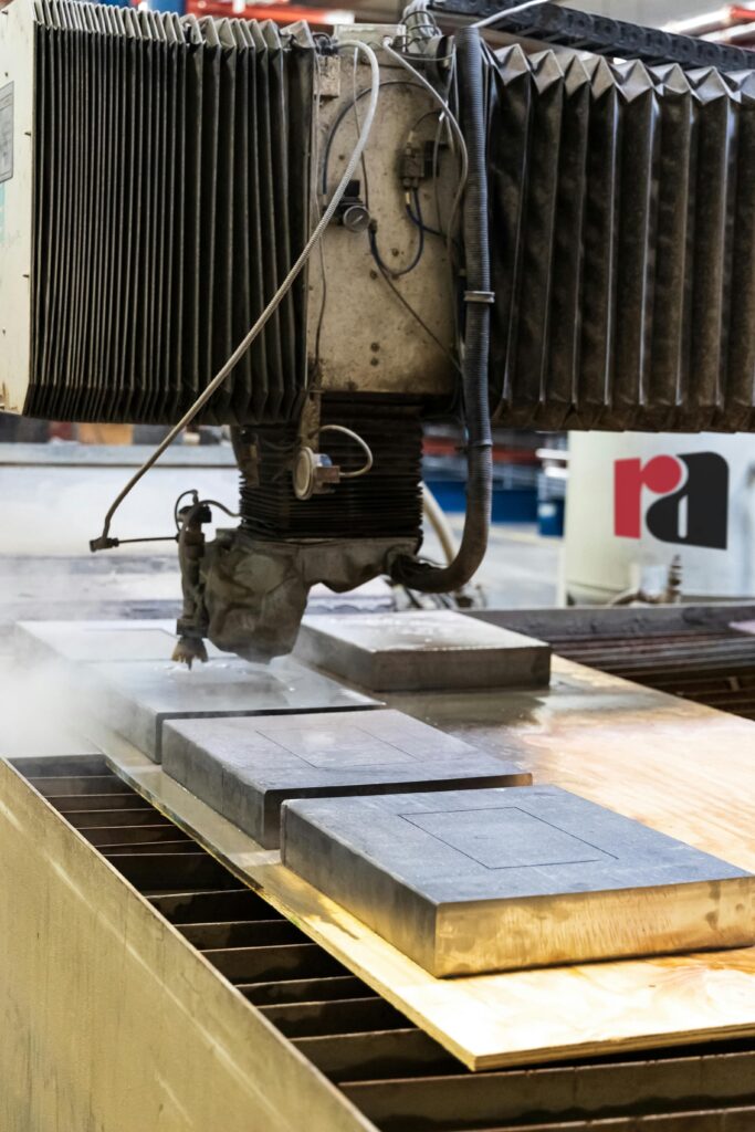 Close-up of a water jet cutting machine slicing through metal in a factory setting.
